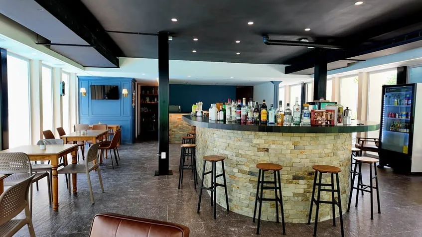 un bar con mesas y sillas en the leaf condos playacar