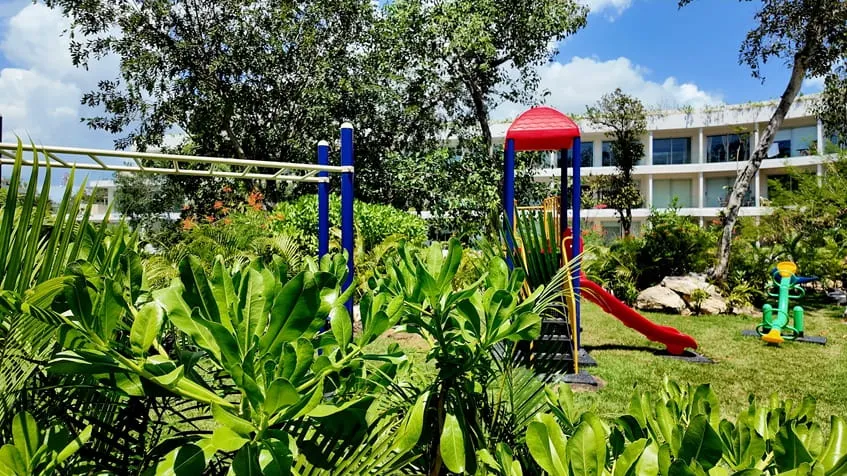 un parque infantil con juegos y areas verdes en the leaf condos playacar
