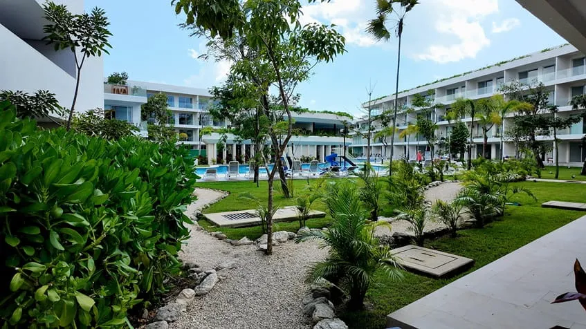 un jardin grande con una alberca al fondo en the leaf condos playacar