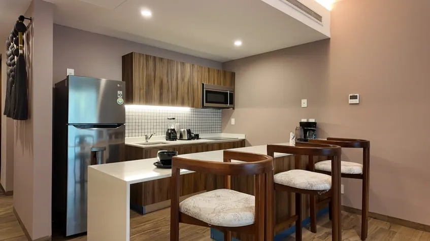 una barra desayunadora, un refrigerador y una cocina en the leaf condos playacar