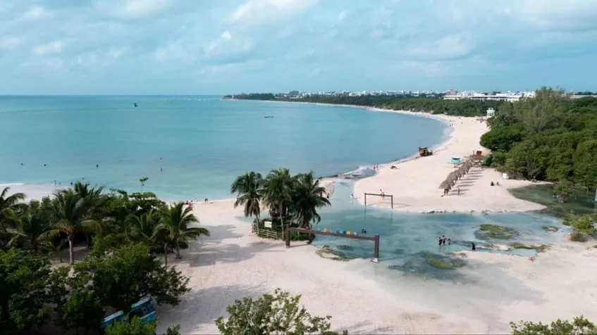 una playa publica con palapas pequeñas alrededor en macondo punta esmeralda playa del carmen