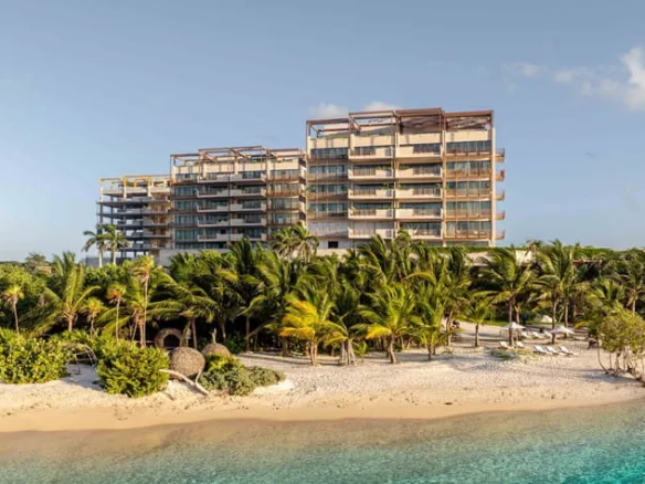 una fachada de un edificio de departamentos frente al mar en costa residences corasol playa del carmen