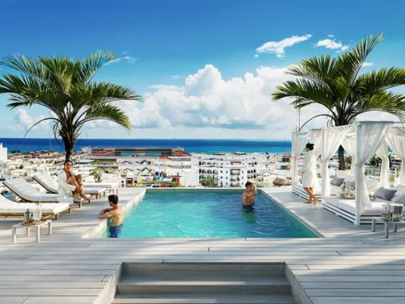 una piscina grande con camastros en menotto 10 playa del carmen