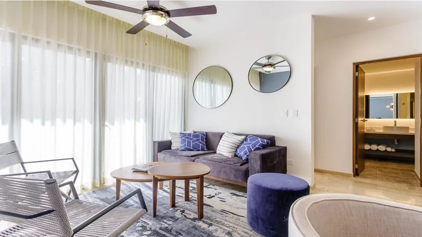 una sala con un sofa elegante y un baño al fondo en ipana playa del carmen